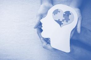 Shape of a head with heart made of jigsaw pieces, being held by a pair of hands
