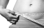 A person measuring their waistline with a tape measure