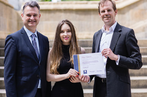 Young woman being handed a certificate award by two men.