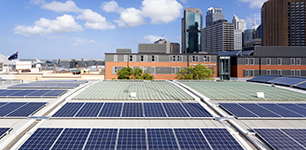 Solar panels on a roof in a city with skyscrapers in the background
