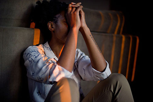 A woman sat on the floor with her head in her hands