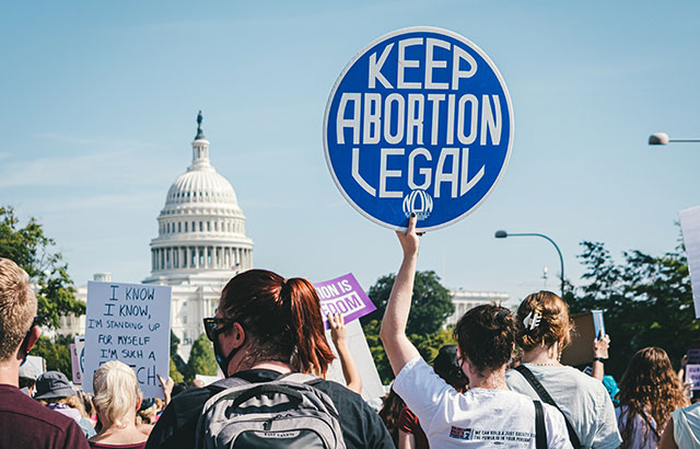 A pro-abortion protest with a person holding a sign saying 'keep abortion legal'