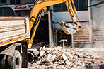A bulldozer clearing away rubble in a residential area.