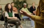 The hands of someone speaking to a group of young people.