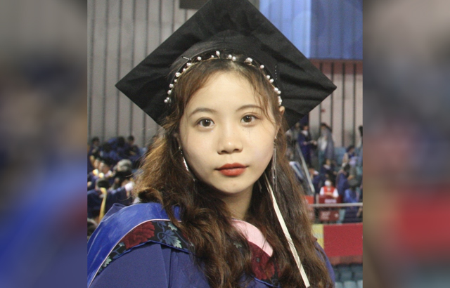 Yijia Lui wearing graduation gown and mortar board.