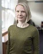 Sara Delm. She has medium blonde hair, and is wearing a green jumper.