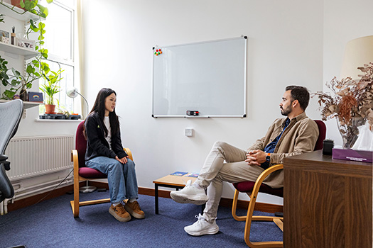 Two people sat in an office having a meeting.
