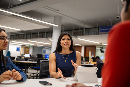 A woman speaking to people around a table in an office.
