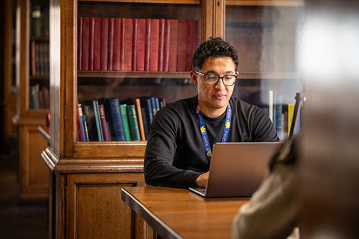 A man at a laptop in the library.