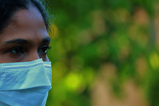 A woman wearing a facemask stood against some forest