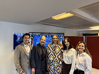 A group of people standing in front of a blue screen in a classroom