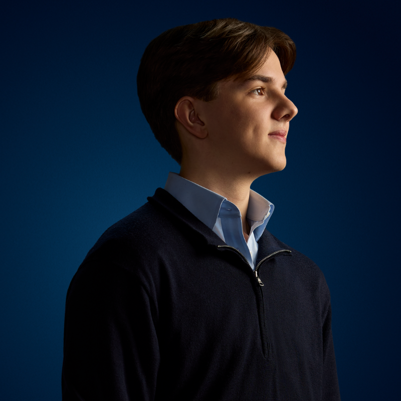 Male dressed in blue shirt and dark jumper looking to the right