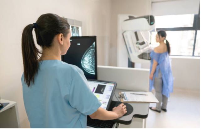 Nurse takes mammogram of woman for breast cancer screening