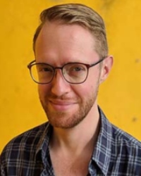 Headshot of Lee Jones wearing a checkered shirt and glasses