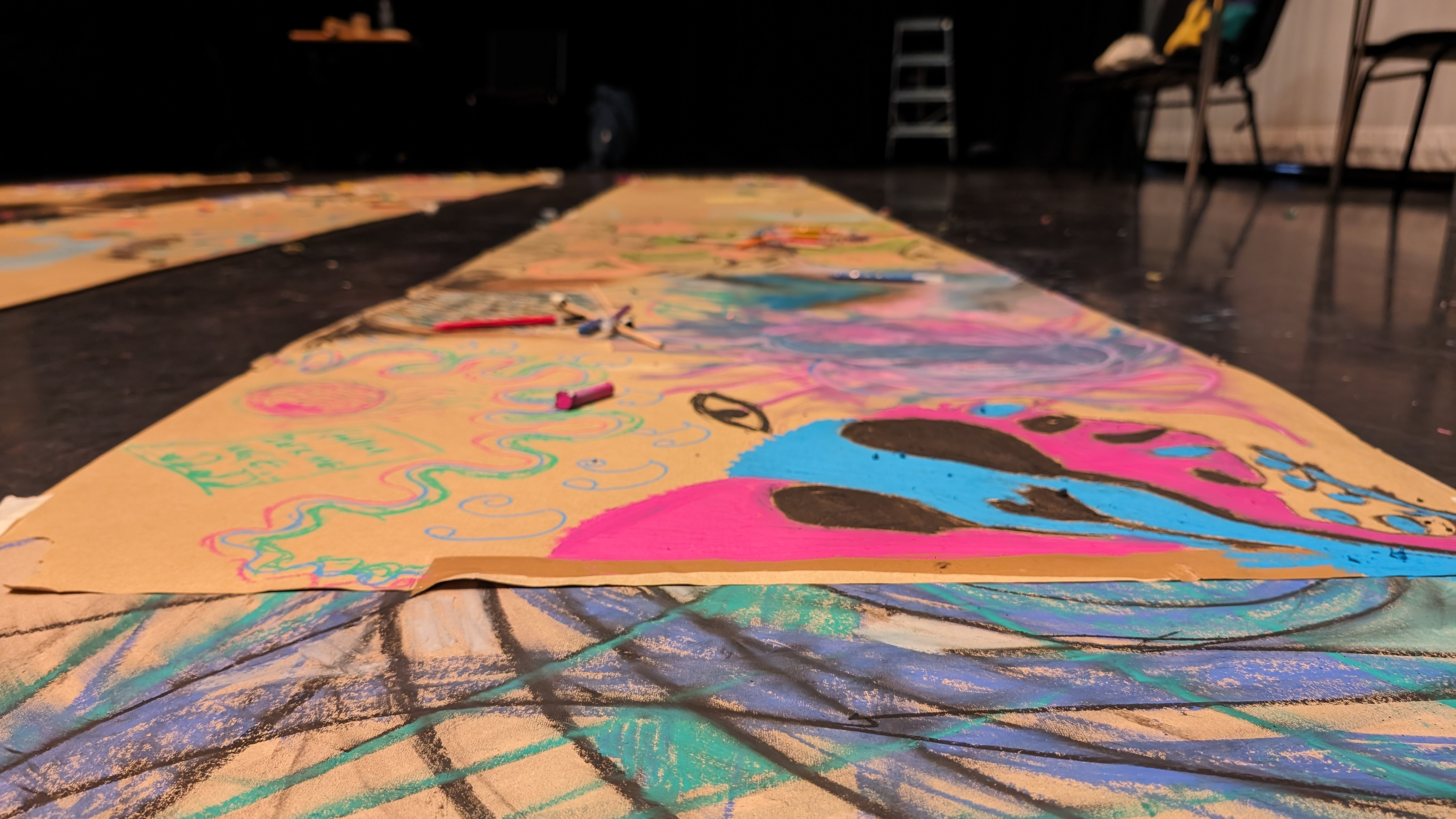 A photo of chalk drawings on tan paper, taken from ground level