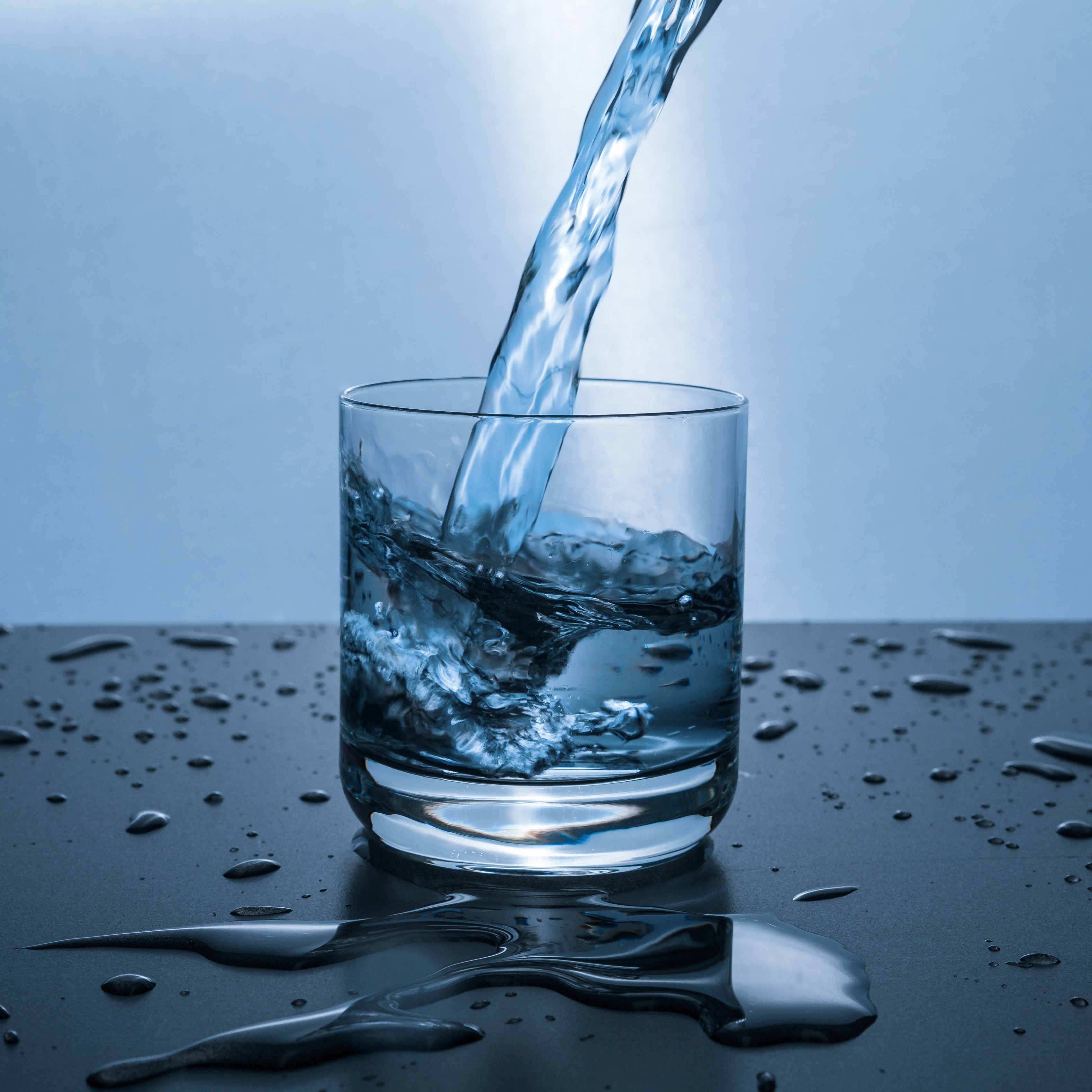 Water being poured into a glass which is already half full.