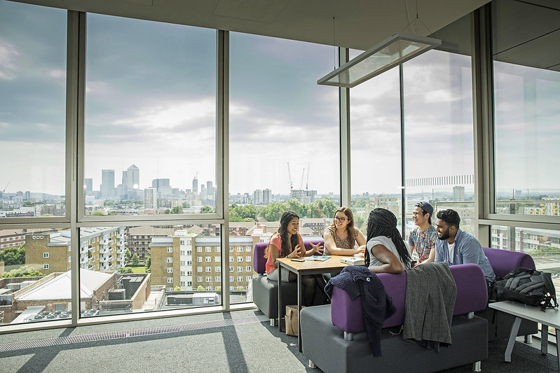 A group of students talking in front of a panoramic city view