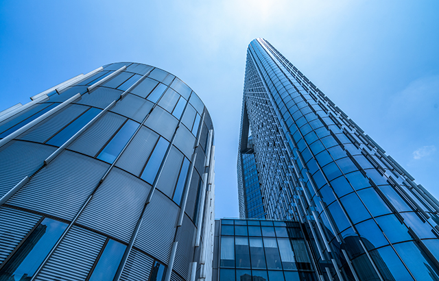 A view looking up from the ground at glass office buildings and a bluesky.